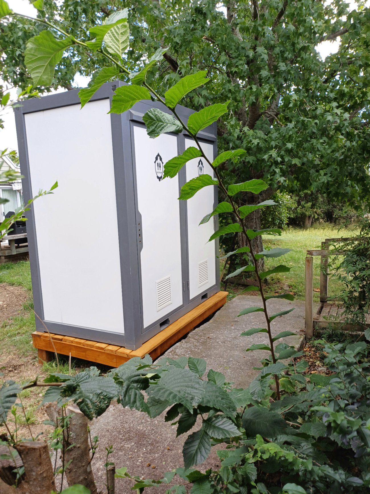 Customer's double toilet installed on a timber deck in a leafy garden